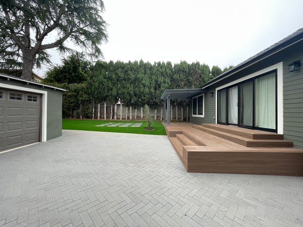 Exterior home renovation with herringbone paver driveway, composite deck, and landscaping by JSP Construction