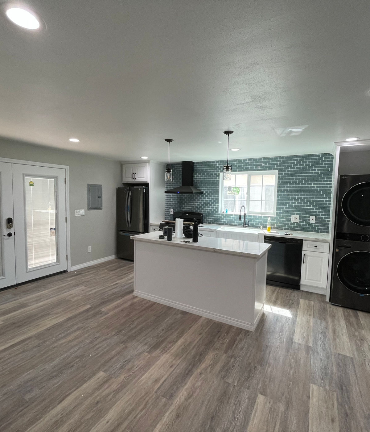 Completed ADU interior with white kitchen island, teal subway tile backsplash, and stainless steel appliances by JSP Construction