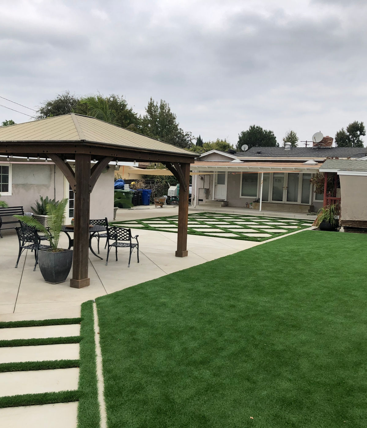 Backyard remodel with wooden gazebo, artificial turf, and diamond paver patio by JSP Construction in Los Angeles